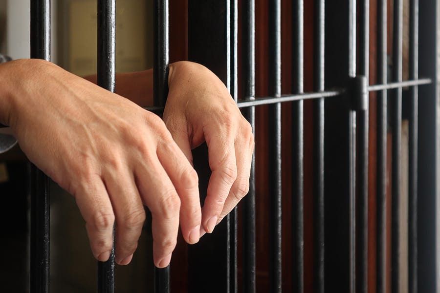 Prisoner behind bars.hand of prisoner on steel jail bars